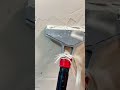 using a long handled scraper tool to remove old plaster or paint from the wall for a fresh surface