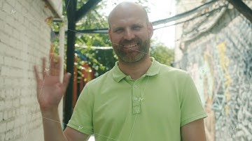 Slow motion portrait of good-looking guy waving hand and smiling looking at camera with friendly