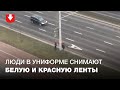 Люди в униформе снимают белую и красную ленты со столба возле станции метро «Михалово»