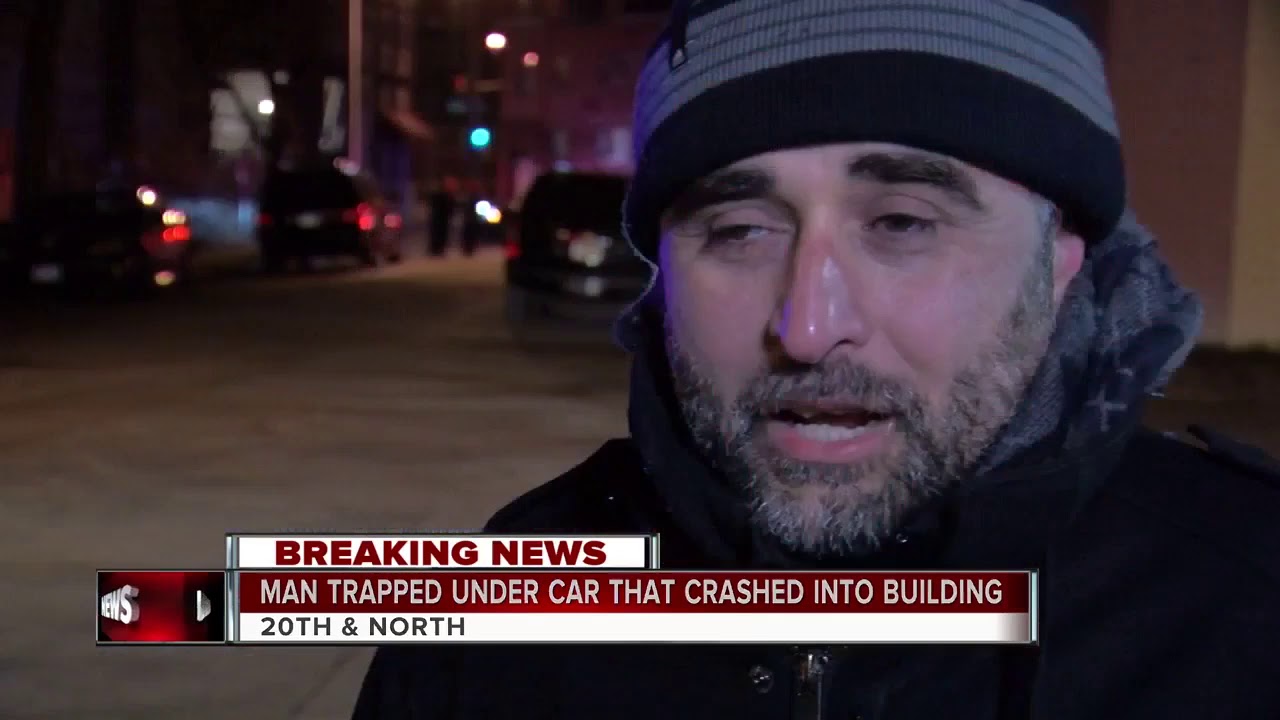Man trapped under a car after a vehicle strikes building - YouTube
