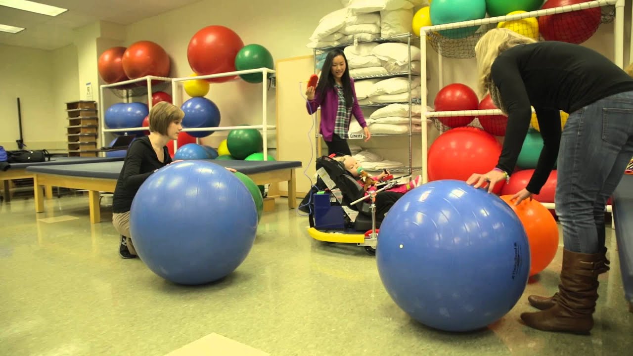 Students watch child in the Play and Mobility Device