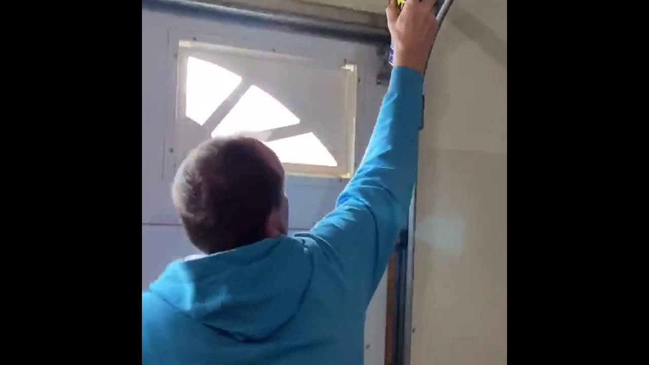 Homeowner DIY maintenance garage door action shot lubrication cleaning tracks
