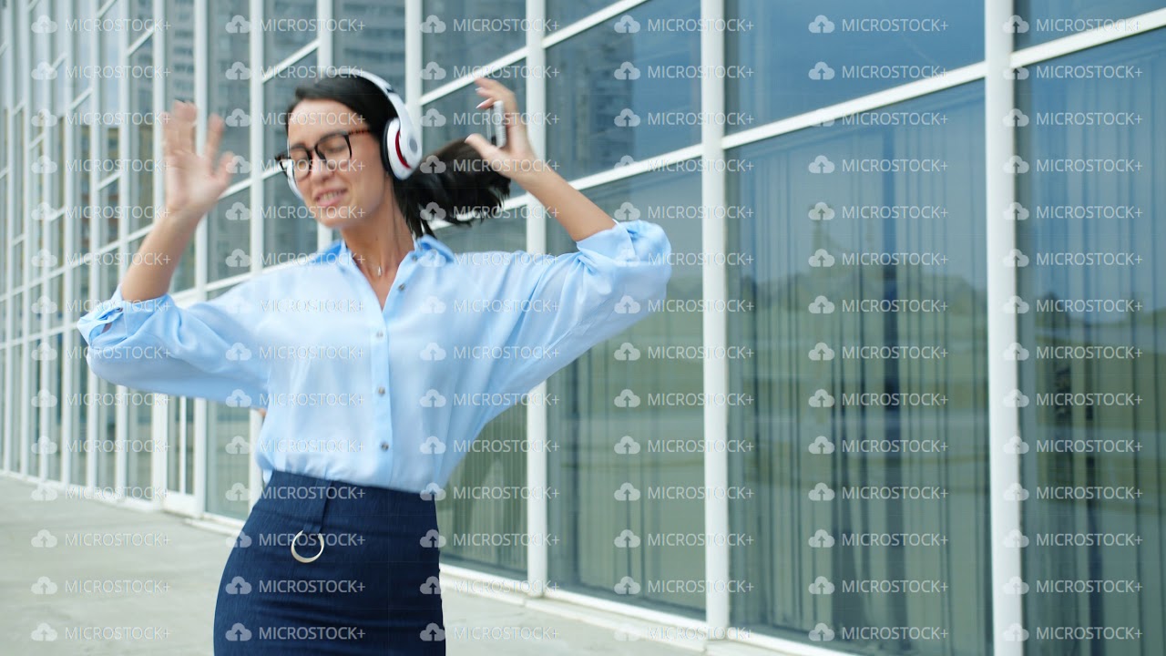 Careless office worker having fun outdoors dancing to music in