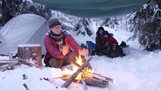 Family Winter Camping In Snow Wonderland Sleeping In Tent Cook Over Fire