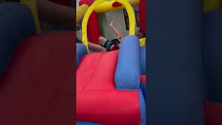 Guy jumps in bounce house while holding little boy and send baby flying in the air