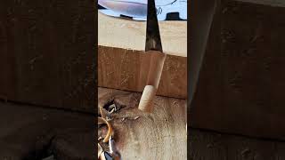 carving a precise vertical groove into a thick block of wood using a sharp metal chisel woodworking