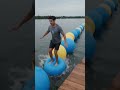 balls on a lake obstacle course. Handheld tracking follows her as she lands on a wooden platform