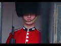 Queen's Royal Foot Guard at Buckingham Palace makes funny faces at a tourists in London.