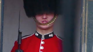 Queen's Royal Foot Guard at Buckingham Palace makes funny faces at a tourists in London.