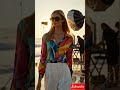beautiful young fashion model walking along a stunning sea beach toward a luxury shooting