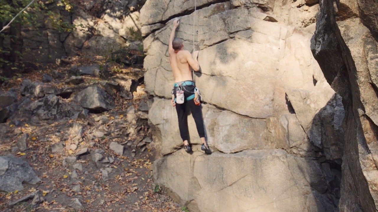 movement stabilized shot of shirtless young man rock climbing searching ...