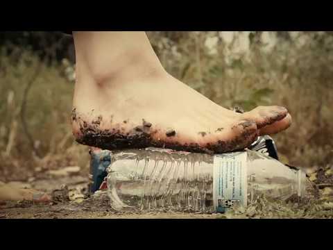 Bare female feet crush empty water bottle