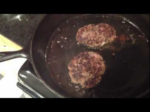 Fresh home ground burgers cooking in bacon grease on cast iron.