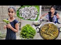 Santali tribe girl cooking Small fish recipe with fresh dheki shak in village style