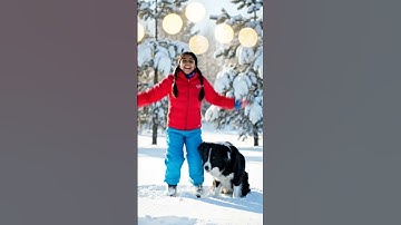 The small girl create a blog video and jumped with dog in a snow ground , soft bokeh