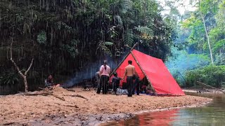 Berkemah di tengah hujan lebat, banyak orang di tempat berteduh di tepi sungai, berkemah dan mema...