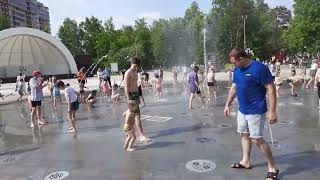 Funny children play with water in the fountain on a hot day