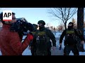 Federal officers push AP reporters back to their car as they document operation