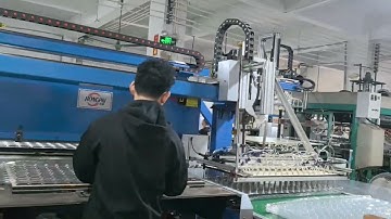 Trimming machine with robot arm in line of thermoforming machine