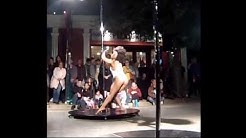 A beautiful pole dancer performin in the street.