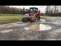 Soil conditioning a gravel parking area and removing potholes svl75 bobcat Harley rake