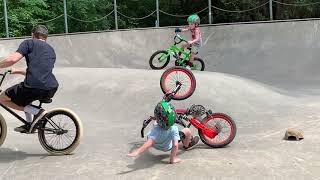BMX rider does backflip from ramp at skatepark and collides into little boy