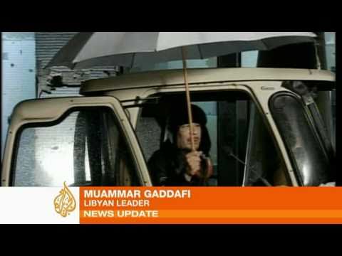 Muammar Gaddafi, Libya's leader of 42 years, appeared briefly under an umbrella to tell viewers that he had planned on sleeping among protesters in Tripoli, the capital, but couldn't because of the rain. State television then went on to broadcast video of an orchestra and singers.