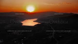 Calm twilight glow illuminating flowing river and nearby valleys with soft clouds