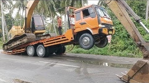 The process of loading an excavator onto a self-loader truck.
