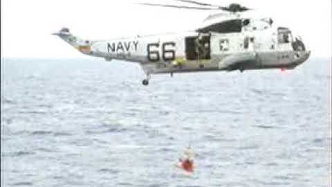 An Apollo 11 crewmember is lifted to the waiting helicopter after splashdown