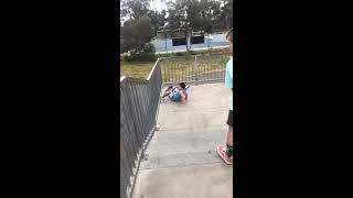 Scooter kid rides up half pipe and crashes into fence at skatepark