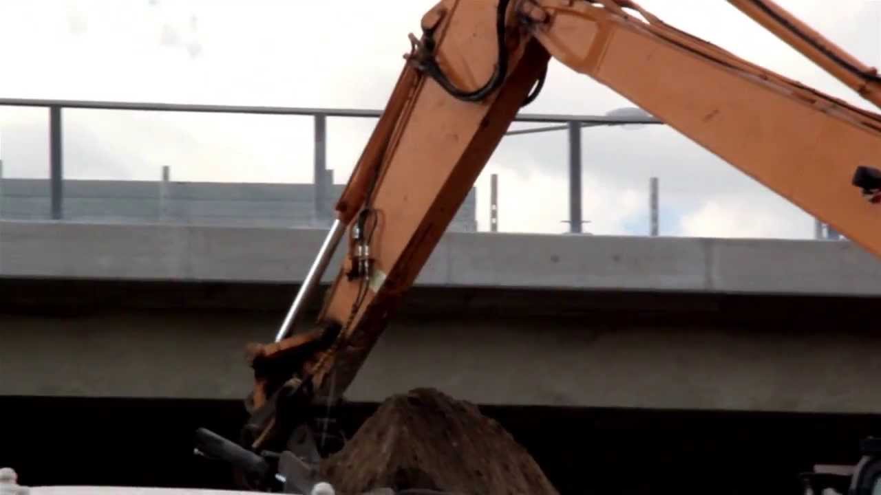 350 Bulldozer loading soil while a person at the bridge passing by