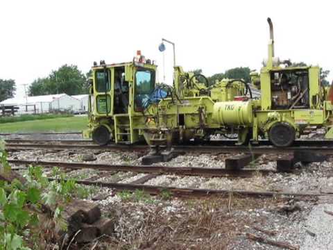 The CSX Railroad tie replacement crew passed through Rensselaer, Indiana on July 28-9, 2009. Video shows machines removing ties, placing new ties along track, and shoving new ties under the track. It also shows placement of spike plates, driving of spikes, and ballast shaping. There were other steps that were not shown. For more information, see rensselaeradventures.blogspot.com