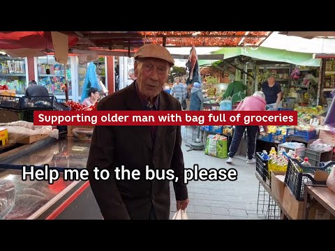 Supporting older man with bag full of groceries