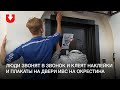 Люди звонят в звонок и клеят наклейки и плакаты на двери ИВС на Окрестина