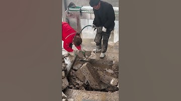 The craftsman holds a high-frequency vibration hammer to break up the indoor floor concrete