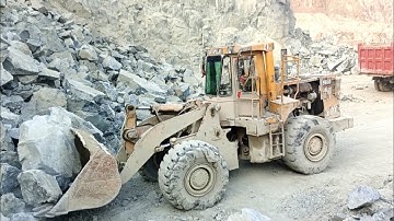 Heavy machine rocks loading in action; Caterpillar loader 966D big rocks loading trolley and dampers