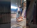 SWINGING AND DROPPING HEAVY MANUAL HAMMER IN REPAIRING EXCAVATOR'S END BOSS IN MECHANICAL WORKSHOP