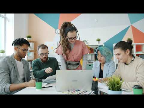 Group of creative young people specialists discussing business looking at laptop in office