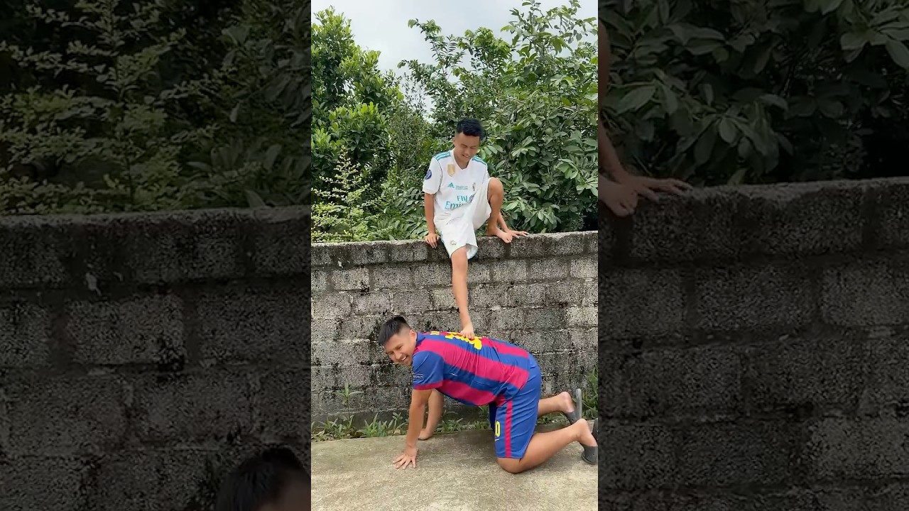 Messi helps Ronaldo get down from the high wall.