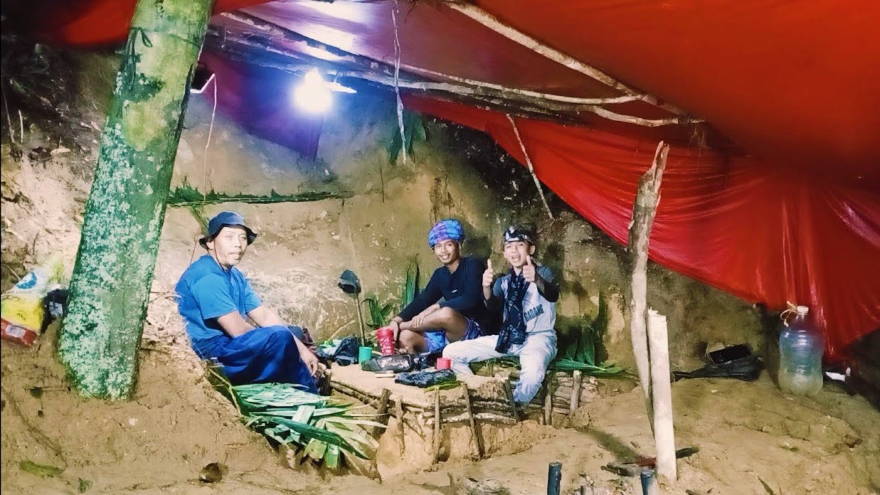 camping hujan deras membuat rumah dalam tanah di samping batu besar