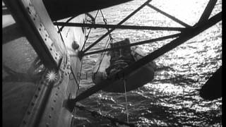 Blimp pulls up life raft and doctor climbs up ladder to airship to treat a patien...HD Stock Footage