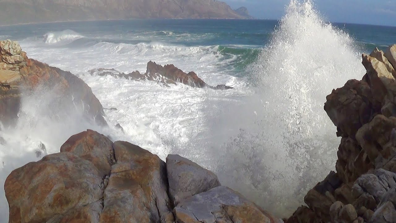 sea with big waves crashing to shore and rocks