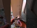 Drywall finisher smooths compound along damaged corner bead edge