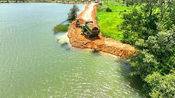 Incredible Mini bulldozer is pushing a new dam as a small dump truck is dumping dirt into a slope