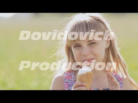 Beautiful blond little girl eats ice-cream in the summer against the background of a wheat field