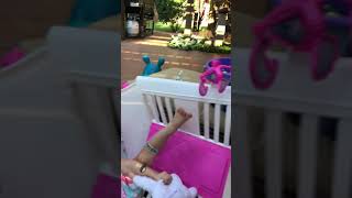 Little girl sits in toy crib with doll that breaks and she falls on the floor