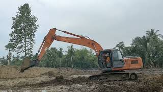 EXCAVATOR HITACHI MANEUVERING IN THE RICEFIELD.