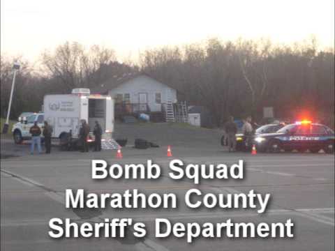 At approximately 5:30pm on October 26, 2009, while driving East on Hwy. 8 towards Turtle Lake, WI, I came upon the scene of what appeared to be a bomb situation. In the early afternoon, according to the onlookers in the Wayne's Cafe parking lot across from the Super America, an unidentified package wrapped in duct tape was found on the exterior of the Super America next to the USPS Mail Box. Law enforcement coordinated off the area and called in the Marathon County Bomb Squad. At 6pm, the bomb squad was attempting to use a robotic arm to remove the object. The following pictures and video were taken by Kirk Anderson of St. Croix Falls, WI. Related Story about the Marathon County Sheriff's Department Bomb Squad www.wsaw.com