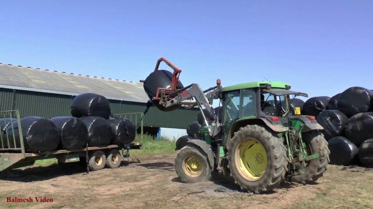Unloading Round Bales with John Deere 6310.
